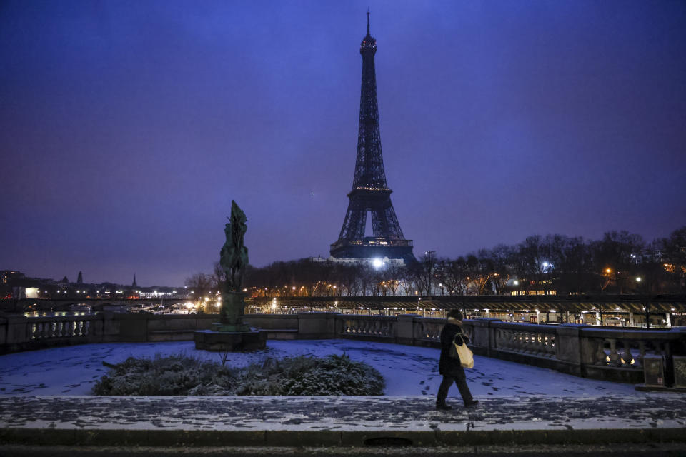 FILE - A woman walks to a bridge in front of the Eiffel Tower after snowfalls, Jan. 18, 2024 in Paris. For the eighth straight month, Earth was record hot, according to the European climate agency’s analysis of January 2024. (AP Photo/Thomas Padilla, File)