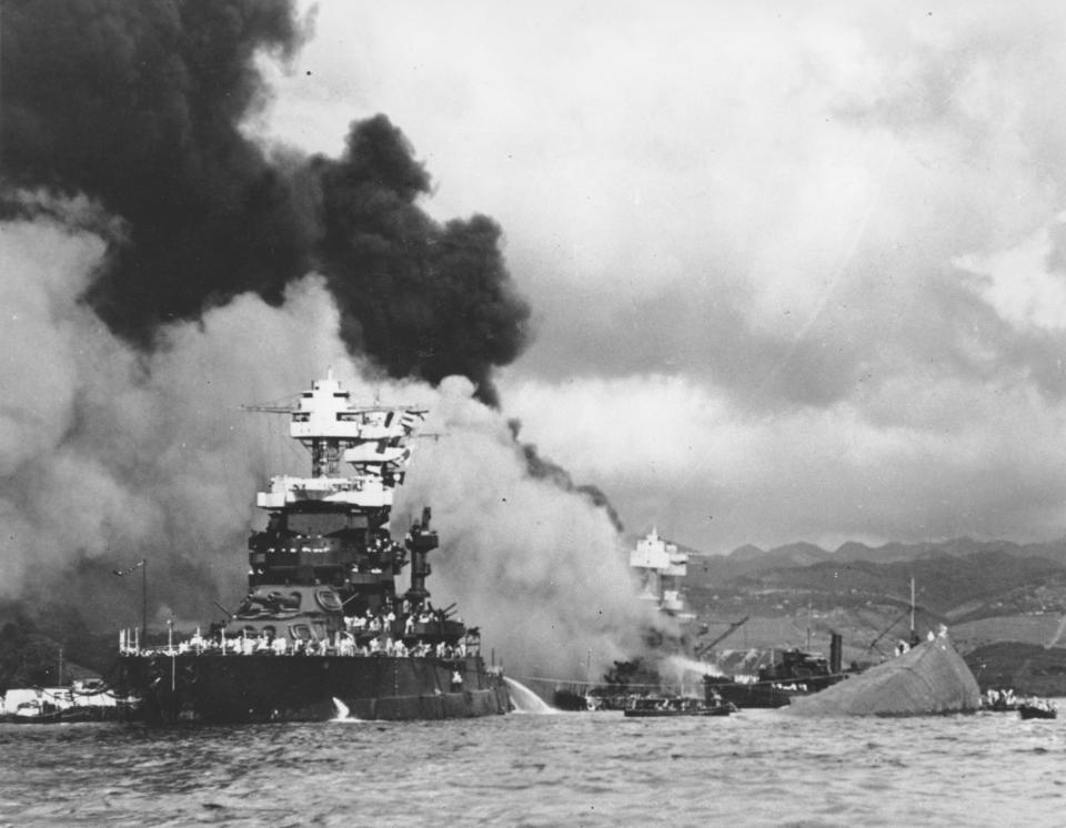 FILE - In this Dec. 7, 1941, file photo, part of the hull of the capsized USS Oklahoma is seen at right as the battleship USS West Virginia, center, begins to sink after suffering heavy damage, while the USS Maryland, left, is still afloat in Pearl Harbor, Oahu, Hawaii. Pearl Harbor survivors and World War II veterans are gathering in Hawaii this week to remember those killed in the Dec. 7, 1941 attack. Those attending will observe a moment of silence at 7:55 a.m., the minute the bombing began. The ceremony will mark the 80th anniversary of the attack that launched the U.S. into World War II. (U.S. Navy via AP, File)