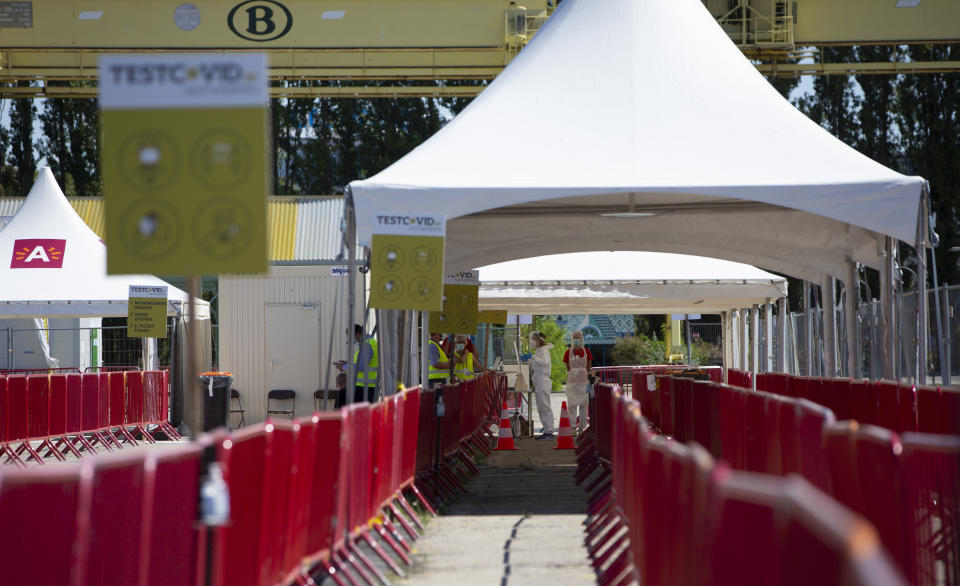 FILE - In this Wednesday, Aug. 5, 2020 file photo, healthcare workers stand in a tent at a drive-thru COVID-19 testing site during a test day in Antwerp, Belgium. With nothing on their agendas for months to come, organizers of music festivals in Belgium want to use their know-how to help the coronavirus vaccination campaign. The Belgian government has set up the goal to vaccine about 70 percent of the country's population, the equivalent of eight million people, when efficient COVID-19 shots become available. (AP Photo/Virginia Mayo, File)