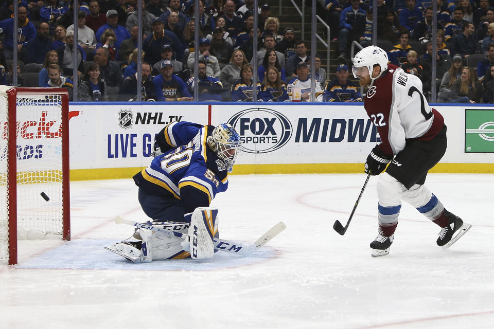 Colorado Avalanche's Colin Wilson (22) watches as St. Louis Blues goaltender Jordan Binnington (50) deflects the puck during the second period of an NHL hockey game Monday, Oct. 21, 2019, in St. Louis. (AP Photo/Scott Kane)