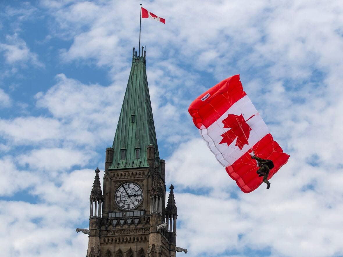 A Skyhawk member glides beside the Peace tower during Canada Day events in Ottawa on Friday. (Lars Hagberg/The Canadian Press/The Associated Press - image credit)