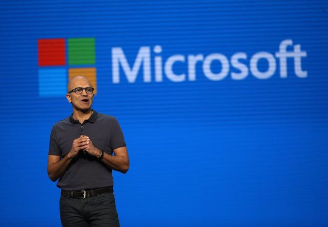 Microsoft CEO Satya Nadella with the word &quot;Microsoft&quot; and the Microsoft logo displayed behind him