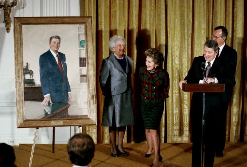 Former President Ronald Reagan and wife Nancy take a peek at a portrait of the former president along with President George H.W. Bush and Mrs. Barbara Bush during an unveiling ceremony at the White House on Wednesday, Nov. 15, 1989. (AP Photo/Barry Thumma)