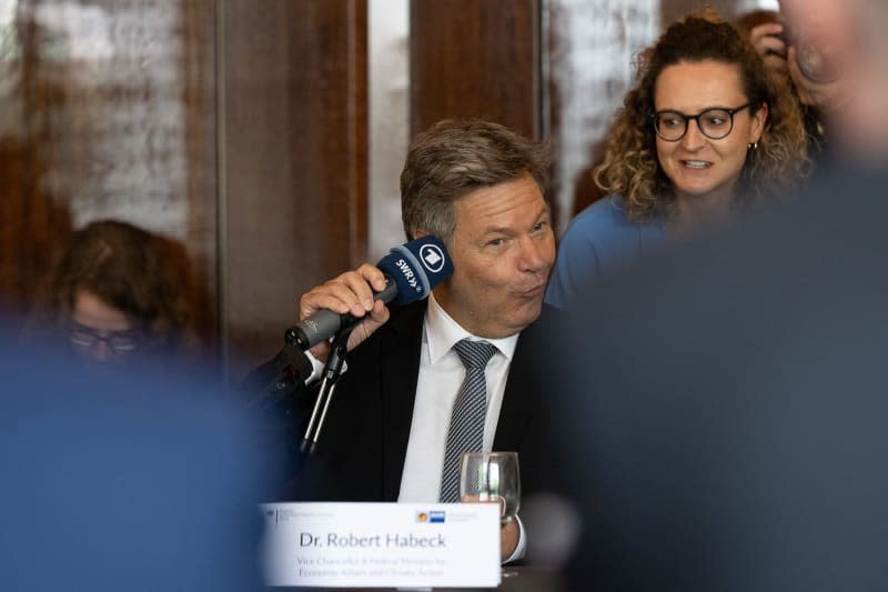 Robert Habeck, Germany's Minister for Economic Affairs and Climate Protection, holds a microphone with the word 