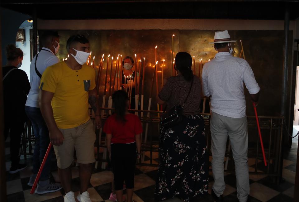 Pilgrims light candles at the Holy Church of Panagia of Tinos, on the Aegean island of Tinos, Greece, on Saturday, Aug. 15, 2020. For nearly 200 years, Greek Orthodox faithful have flocked to Tinos for the August 15 feast day of the Assumption of the Virgin Mary, the most revered religious holiday in the Orthodox calendar after Easter. But this year there was no procession, the ceremony _ like so many lives across the globe _ upended by the coronavirus pandemic. (AP Photo/Thanassis Stavrakis)