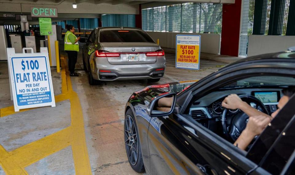 A parking attendent talks to arrivals, explaining the $100 flat rate for anyone except Miami Beach residents and local business employees at a city garage at 400 W. 42nd St., on Thursday, March 7, 2024. Most public parking garages and lots south of 42nd Street will be entirely closed this weekend for spring break in Miami Beach, Florida.