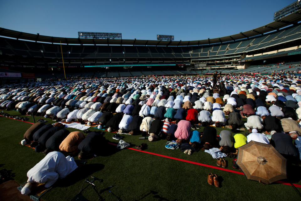 Dr. Muzammil Siddiqi of the Islamic Society of Orange County (L) prays with Muslims gathered for the celebration of the Eid al-Fitr holiday, the end of the holy month of Ramadan at Angel Stadium of Anaheim in Anaheim, California, U.S., June 25, 2017.&nbsp;