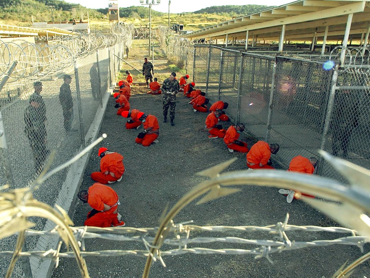 Taliban and al Qaeda detainees in orange jumpsuits in a holding area at Camp X-Ray at Naval Base Guantanamo Bay, Cuba: Getty