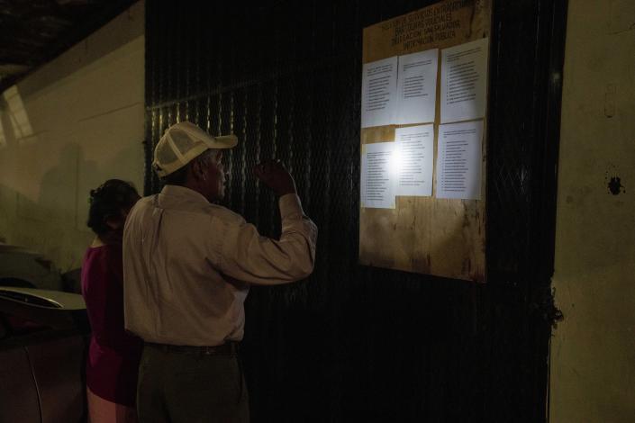 A man uses his phone to illuminate lists of people detained under the ongoing "state of exception", outside a detention center in San Salvador, El Salvador, Tuesday, Oct. 11, 2022. Under the state of exception, the right of association, the right to be informed of the reason for an arrest and access to a lawyer are suspended. The government also can intervene in the calls and mail of anyone they consider a suspect. The time someone can be held without charges is extended from three days to 15 days. (AP Photo/Moises Castillo)