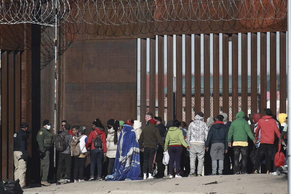 A U.S. Border Patrol stands before a line of migrants before letting the group enter into El Paso, Texas, from Ciudad Juarez, Mexico, Wednesday, Dec. 21, 2022. Migrants gathered along the Mexican side of the southern border Wednesday as they waited for the U.S. Supreme Court to decide whether and when to lift pandemic-era restrictions that have prevented many from seeking asylum. (AP Photo/Christian Chavez)