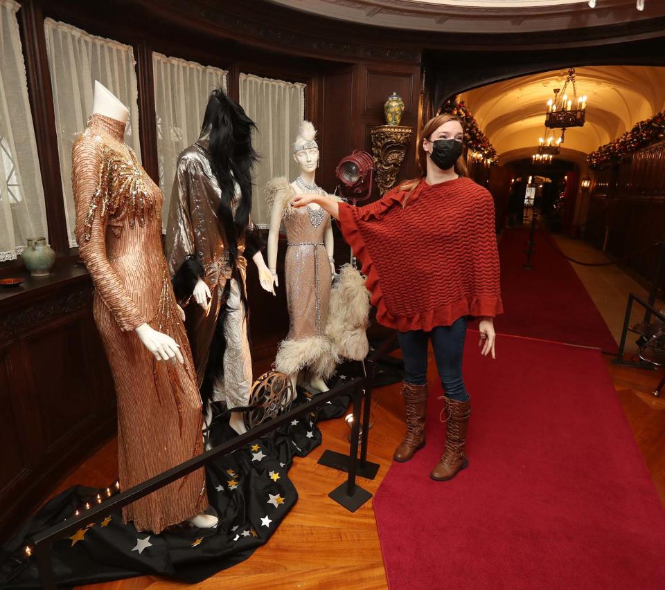 Chloe Wingard, curatorial projects specialist at Stan Hywet, points out features on designer gowns on loan from a local collector.