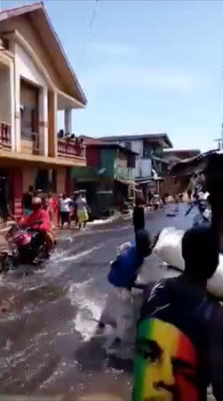 Residents commute though floodwater in the town of Foulah, following Monday's mudslide on the outskirts of Freetown, Sierra Leone, in this still image obtained from a social media video taken August 15, 2017. Kelvin Kamara and Fuhard Sesay / Social Media Website via REUTERS. THIS IMAGE HAS BEEN SUPPLIED BY A THIRD PARTY. NO RESALES. NO ARCHIVES. MANDATORY CREDIT.