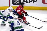 Chicago Blackhawks center Jonathan Toews (19) controls the puck against Vancouver Canucks defenseman Quinn Hughes (43) and defenseman Tucker Poolman during the second period of an NHL hockey game in Chicago, Thursday, Oct. 21, 2021. (AP Photo/Nam Y. Huh)