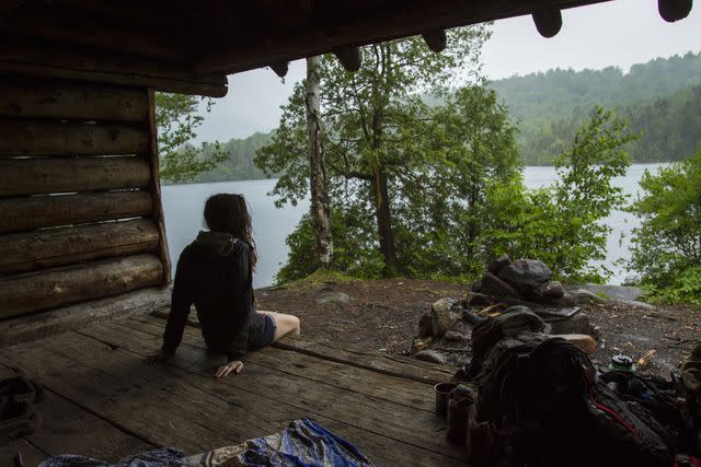 <p>Cavan Images/Getty Images</p> A woman camping in the Adirondack Mountains