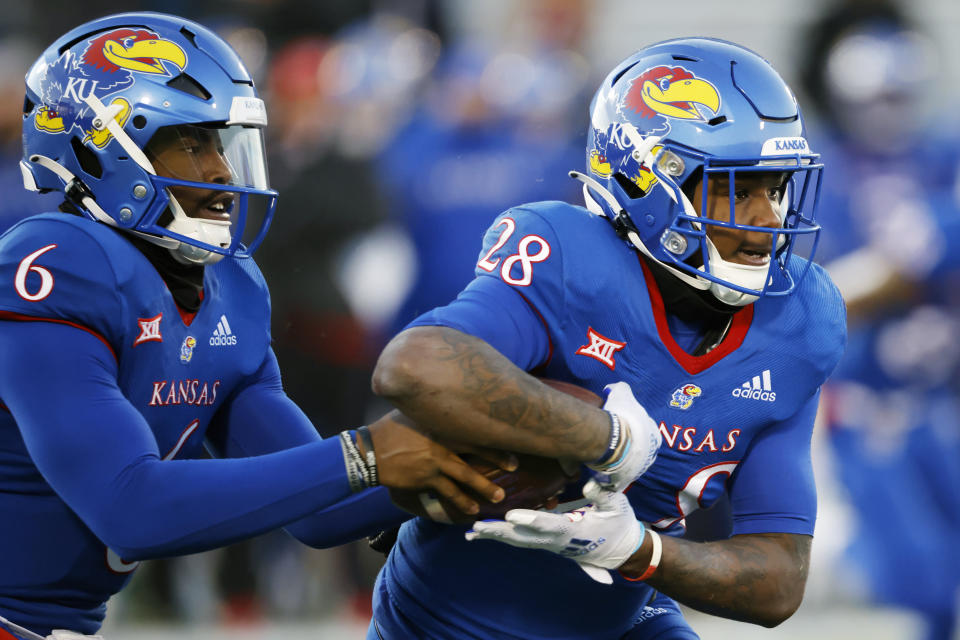 Kansas quarterback Jalon Daniels (6) hands the ball off to Kansas running back Sevion Morrison (28) during the third quarter of an NCAA college football game against Texas on Saturday, Nov. 19, 2022, in Lawrence, Kan. (AP Photo/Colin E. Braley)