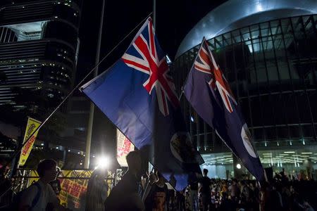 Pro-democracy protesters wave former Hong Kong colonial flags during a demonstration outside Legislative Council in Hong Kong, China June 17, 2015. REUTERS/Tyrone Siu