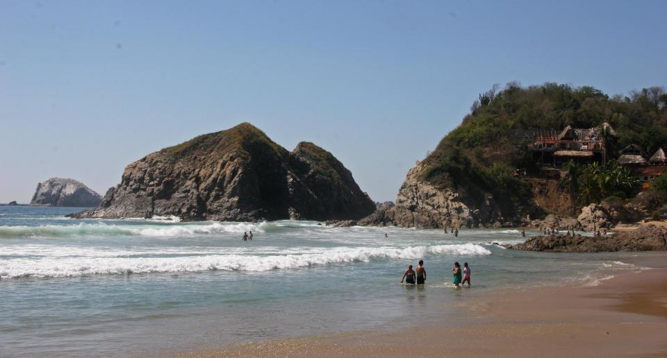 This Dec. 18, 2012 photo shows visitors bathing in the surf along the beach in Zipolite, Mexico. A sleepy town with one main street and no ATMs, Zipolite is one many tiny coastal pueblos that dot the Pacific in Mexico's Southern state of Oaxaca. (AP Photo/Jody Kurash)