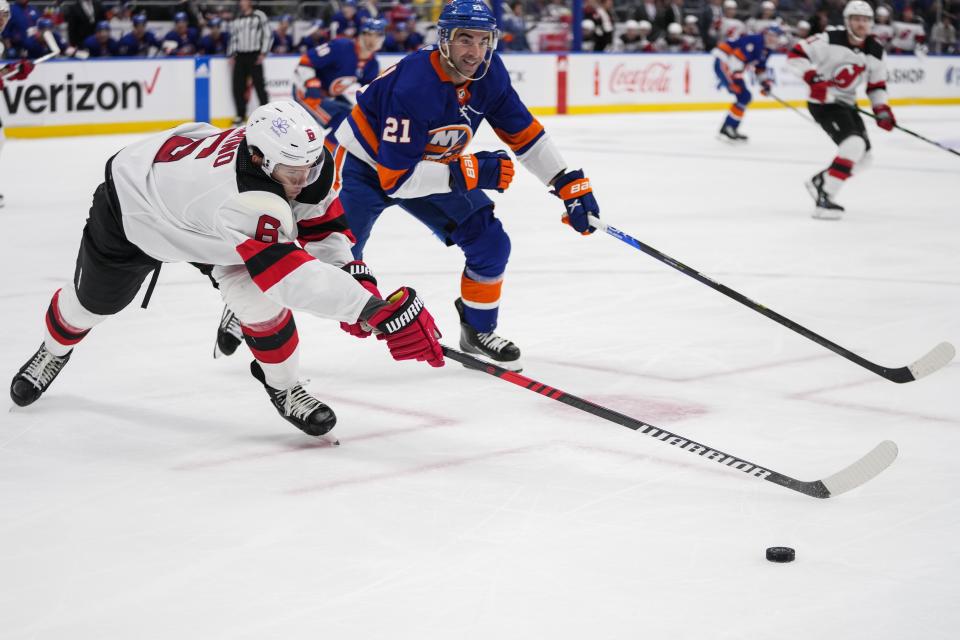 New Jersey Devils' John Marino (6) fights for control of the puck with New York Islanders' Kyle Palmieri (21) during the second period of an NHL hockey game Friday, Oct. 20, 2023, in Elmont, N.Y. (AP Photo/Frank Franklin II)