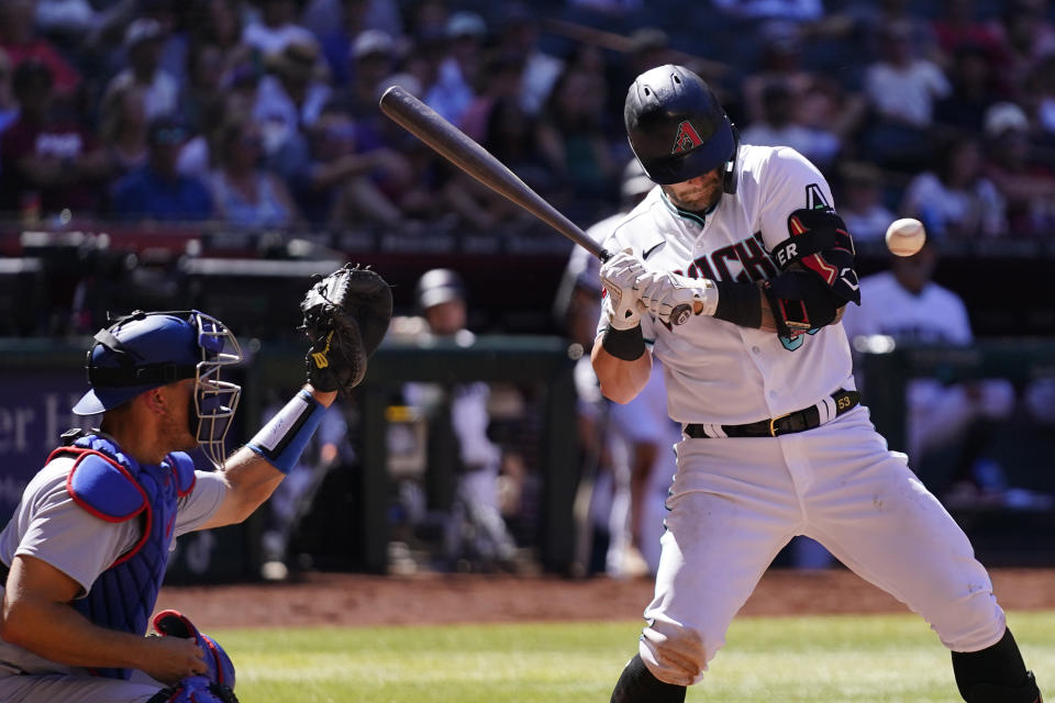 Arizona Diamondbacks' Christian Walker, right, backs off an inside pitch as Los Angeles Dodgers catcher Austin Barnes, left, reaches for the ball during the fifth inning of a baseball game Sunday, April 9, 2023, in Phoenix. (AP Photo/Ross D. Franklin)