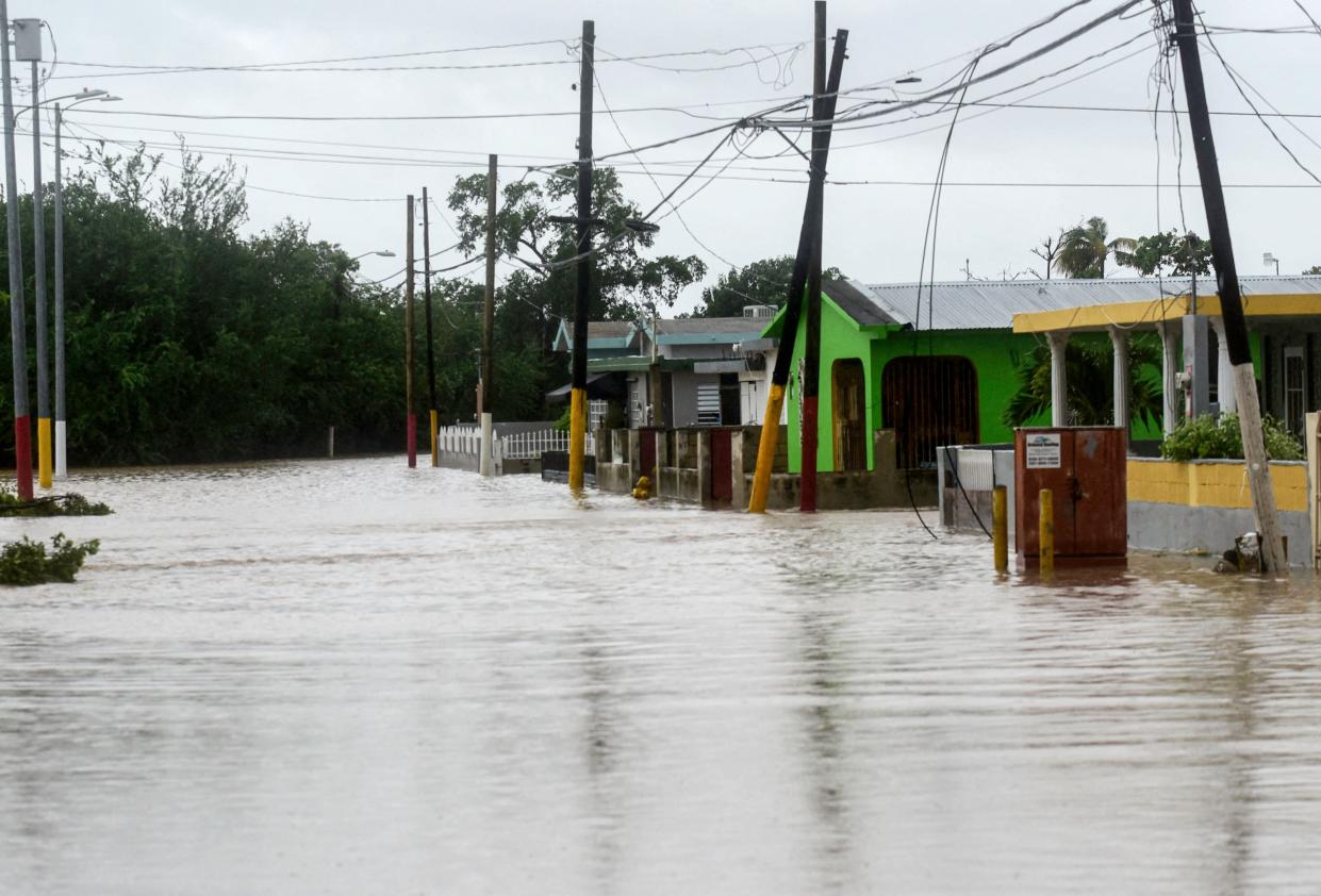 A flooded street lined with partially submerged telephone poles and one-story buildings.