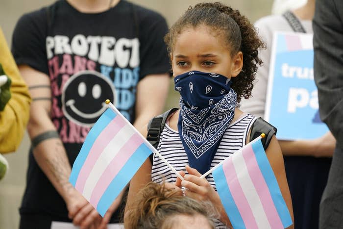 A child holds a pair of trans pride flags on the steps of the Mississippi Capitol in Jackson as they protest House Bill 1125, which bans gender-affirming care for trans children, on Feb. 15, 2023.