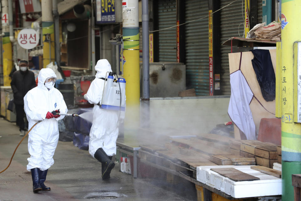 Trabajadores con equipo protector rocían desinfectante como medida preventiva contra el coronavirus en un mercado local en Busan, Corea del Sur, el domingo 23 de febrero de 2020. (Son Hyung-joo/Yonhap vía AP)