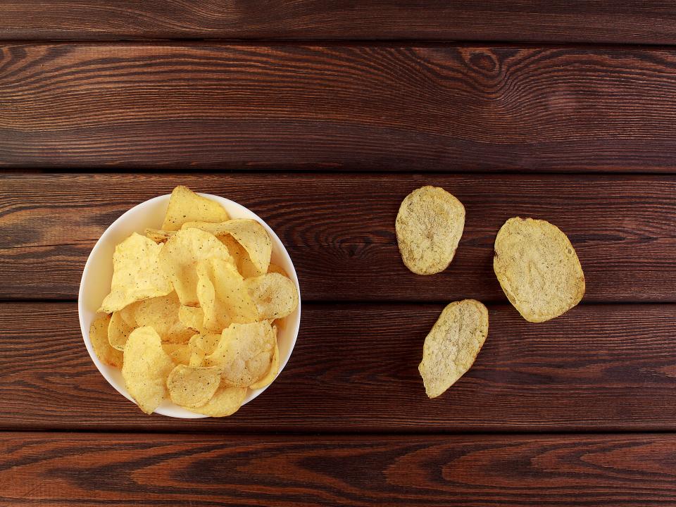 Potato chips in a bowl with a few laid out to the side.