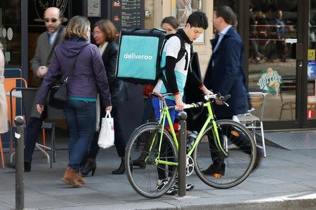 A cyclist prepares to mount a bicycle as he delivers a food order for Deliveroo, an example of the emergence of what is known as the 'gig economy', in Paris, France, April 7, 2017. Picture taken April 7, 2017. REUTERS/Charles Platiau