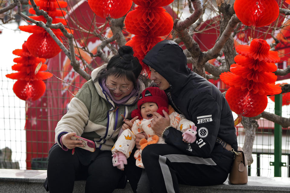 A couple take a selfie with their toddler in front of Lunar New Year decorations at a public park in Beijing, Thursday, Jan. 19, 2023. China on Thursday accused "some Western media" of bias, smears and political manipulation in their coverage of China's abrupt ending of its strict "zero-COVID" policy, as it issued a vigorous defense of actions taken to prepare for the change of strategy. (AP Photo/Andy Wong)