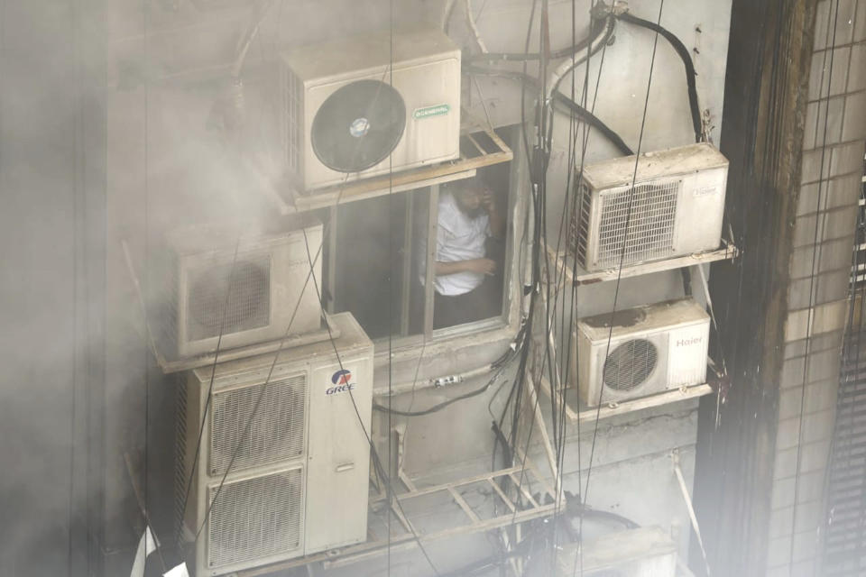 A Bangladeshi, stuck in a multi-storied office building on fire, speaks on his mobile phone in Dhaka, Bangladesh, March 28, 2019. (AP Photo/Mahmud Hossain Opu)