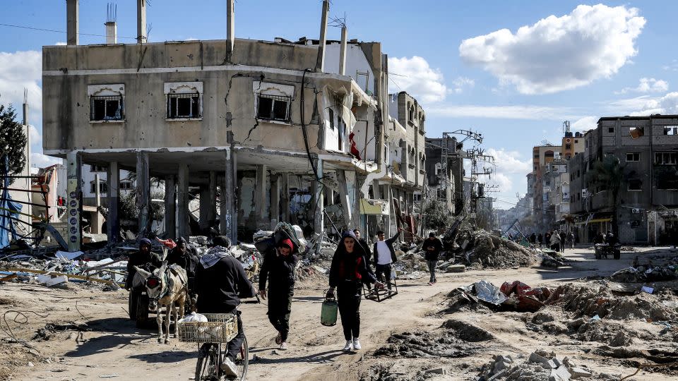 Palestinians walk past buildings destroyed by Israel's bombardment at Al-Maghazi refugee camp in central Gaza, on February 1. - Anas Baba/AFP/Getty Images