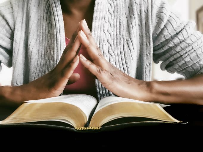 close up of unrecognizable black woman praying while reading scripture