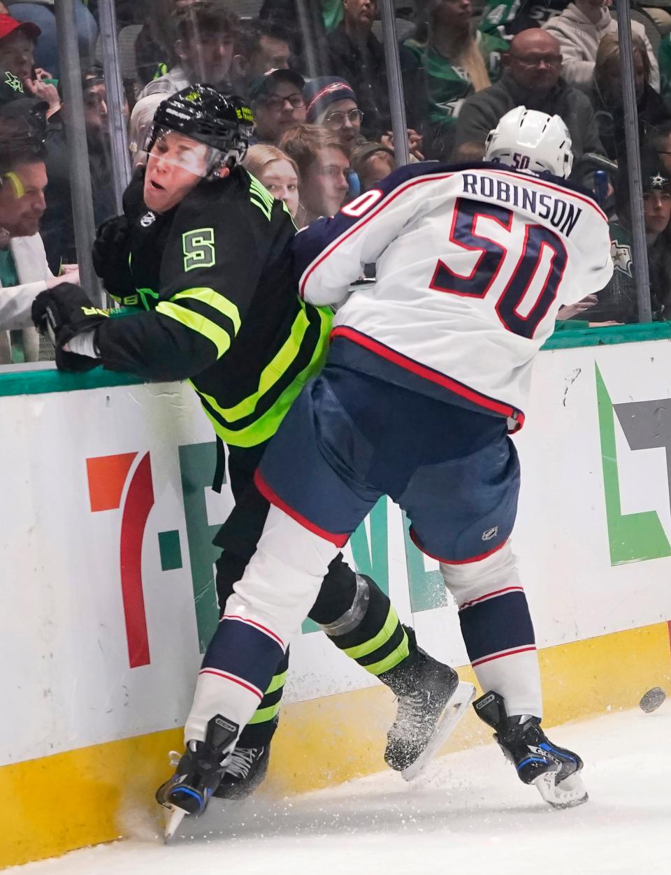 Columbus Blue Jackets left wing Eric Robinson (50) hits Dallas Stars defenseman Nils Lundkvist (5) into the boards during the second period of an NHL hockey game in Dallas, Saturday, Feb. 18, 2023. (AP Photo/LM Otero)