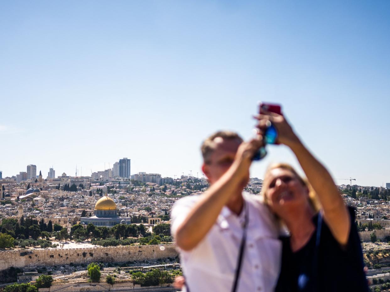 Tourists take selfies on the Mount of Olives overlooking the old city of Jerusalem on June 12, 2023.