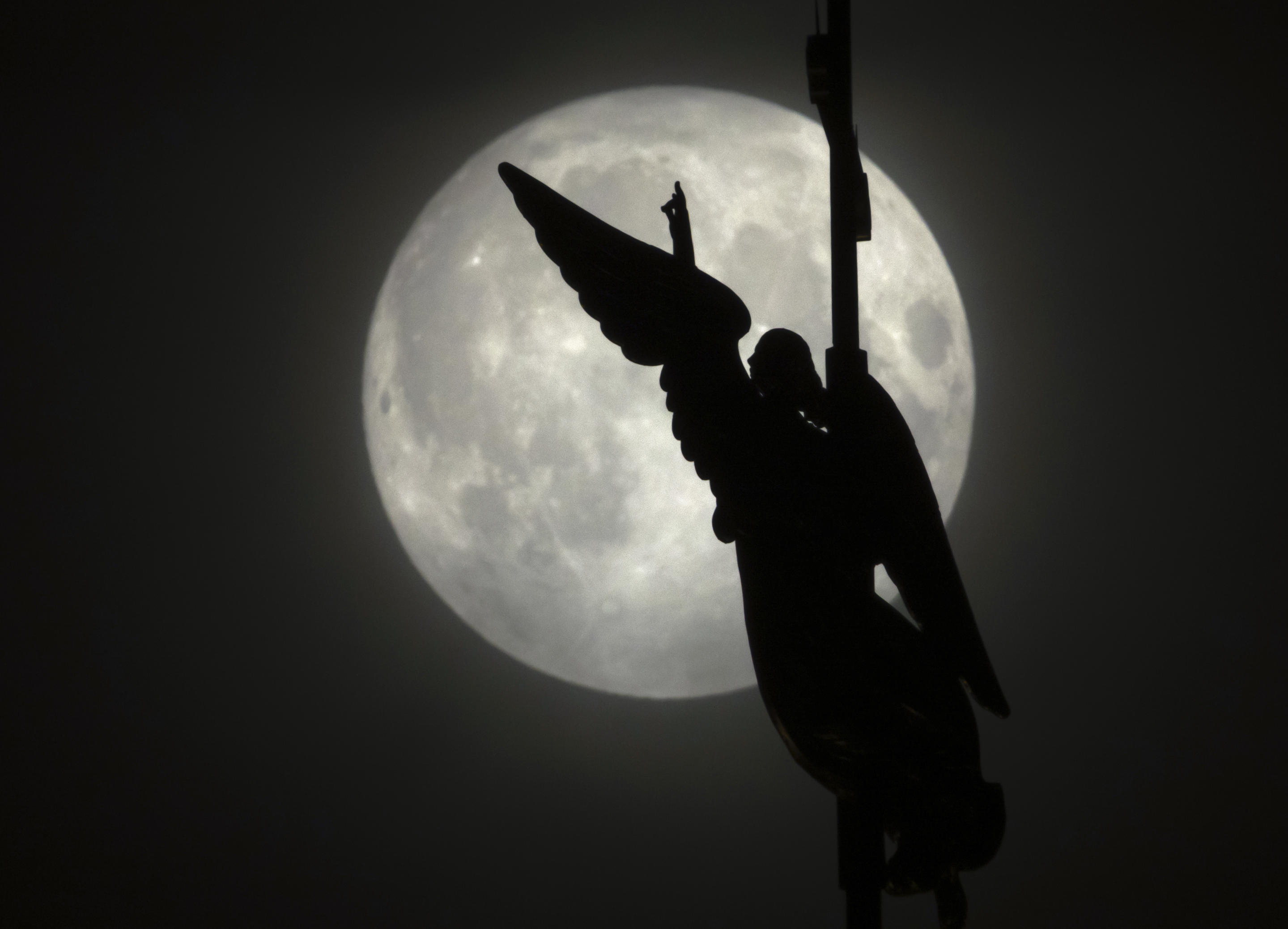 An angel weather vane atop a spire of the Saints Peter and Paul Cathedral, is silhouetted by the rising full moon, Sept. 17., in St. Petersburg, Russia. (Dmitri Lovetsky/AP)