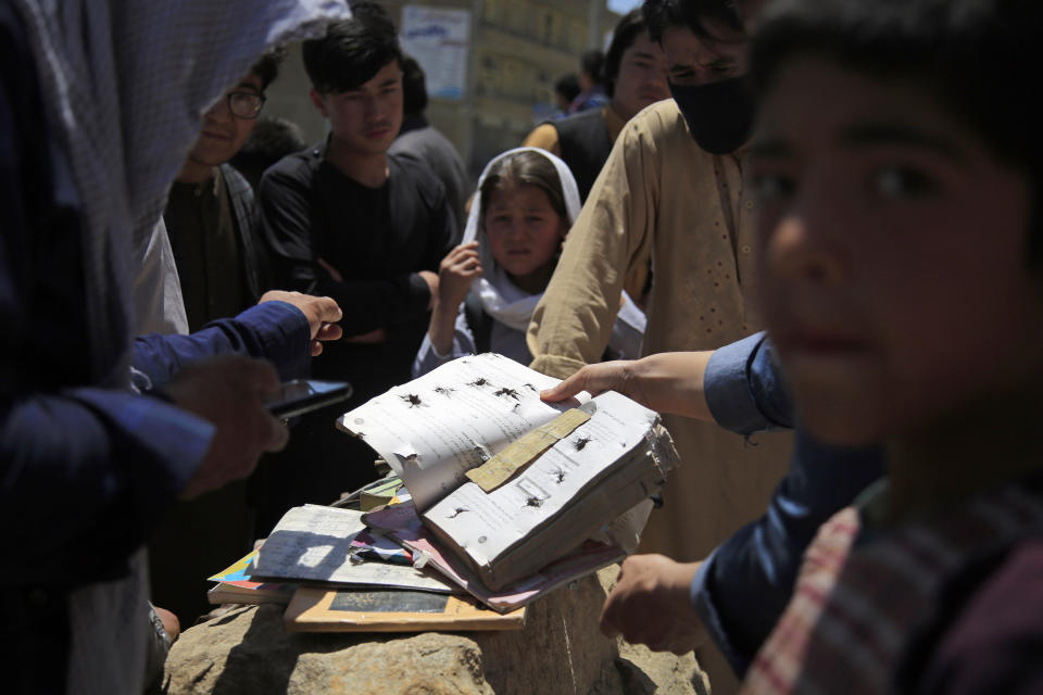 Afghans go through belongings left behind after deadly bombings on Saturday near a school in Kabul, Afghanistan, Sunday, May 9, 2021. The Interior Ministry said the death toll in the horrific bombing at the entrance to a girls' school in the Afghan capital has soared to some 50 people, many of them pupils between 11 and 15 years old, and the number of wounded in Saturday's attack has also climbed to more than 100. (AP Photo/Mariam Zuhaib)