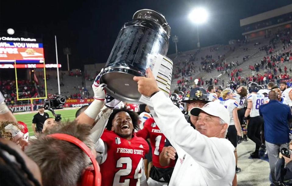 Fresno State head coach Jeff Tedford, right, hoists the milk can after the Bulldogs beat Boise State 37-30 in the Battle for the Milk Can Saturday, Nov. 4, 2023 in Fresno.