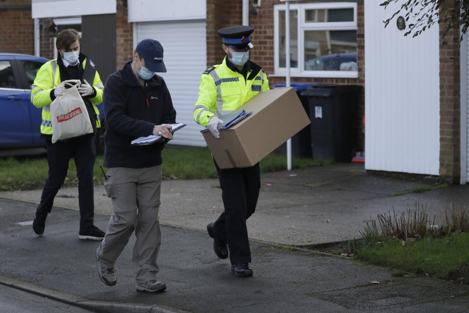 A police volunteer carries a box of home testing kits for COVID-19 from Britain's Department of Health as they go house-to-house distributing them to residents, in Woking, England, Tuesday, Feb. 2, 2021, during England's third national lockdown since the coronavirus outbreak began. British health authorities plan to test tens of thousands of people in a handful of areas of England, including parts of Woking, in an attempt to stop a new variant of the coronavirus first identified in South Africa spreading in the community. The Department of Health says a small number of people in England who had not travelled abroad have tested positive for the strain. (AP Photo/Matt Dunham)