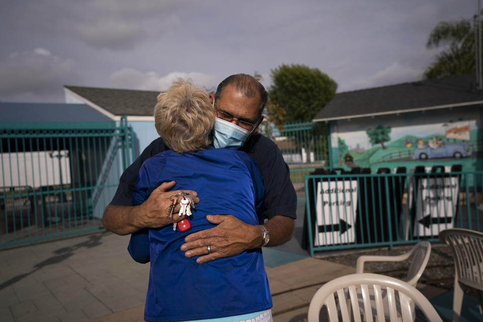 Maintenance department's Lester Green, 68, gets a hug from Yvonne Ansdell, 77, mother of Allan Ansdell Jr, owner and president of Adventure City amusement park, as they prepare for the reopening of the amusement park in Anaheim, Calif., Wednesday, April 14, 2021. Green was among a handful of employees who kept the job after the coronavirus pandemic forced the amusement park to close March last year. "I love it. I'm excited about it" said Green about the park's reopening. "I'm very happy that they (his coworkers) are coming back." (AP Photo/Jae C. Hong)