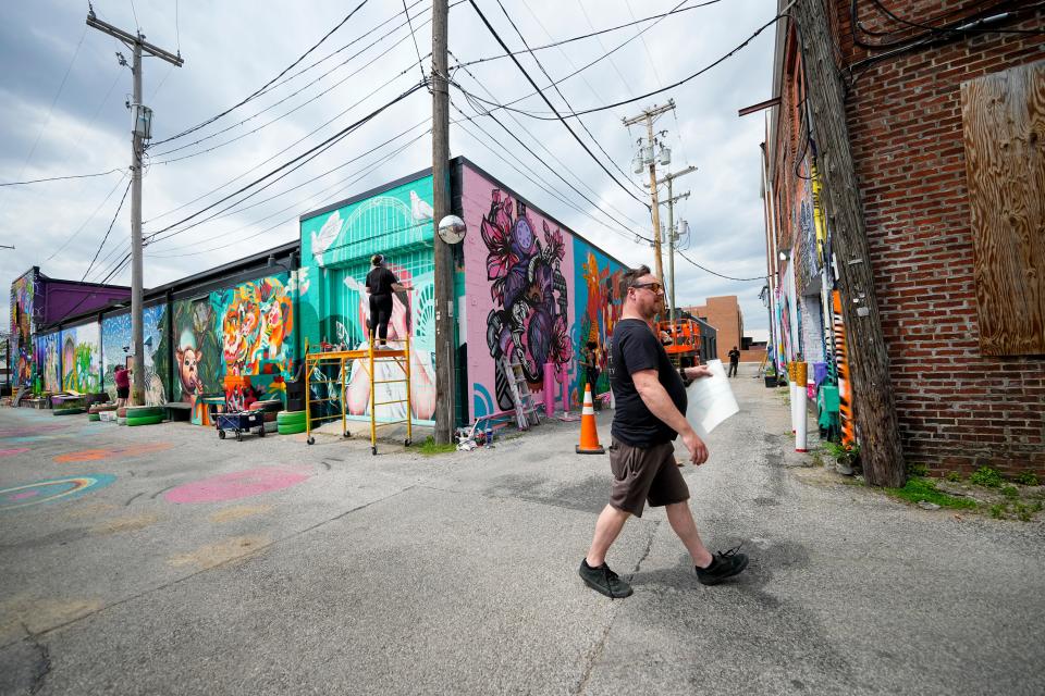 Alley Islands Street Festival's Adam Brouillette oversees the mural-painting on Lafayette Street between Fourth Street and Grant Avenue. Brouillette commissioned 35 artists to paint 10 buildings for the festival, which takes place on Saturday.