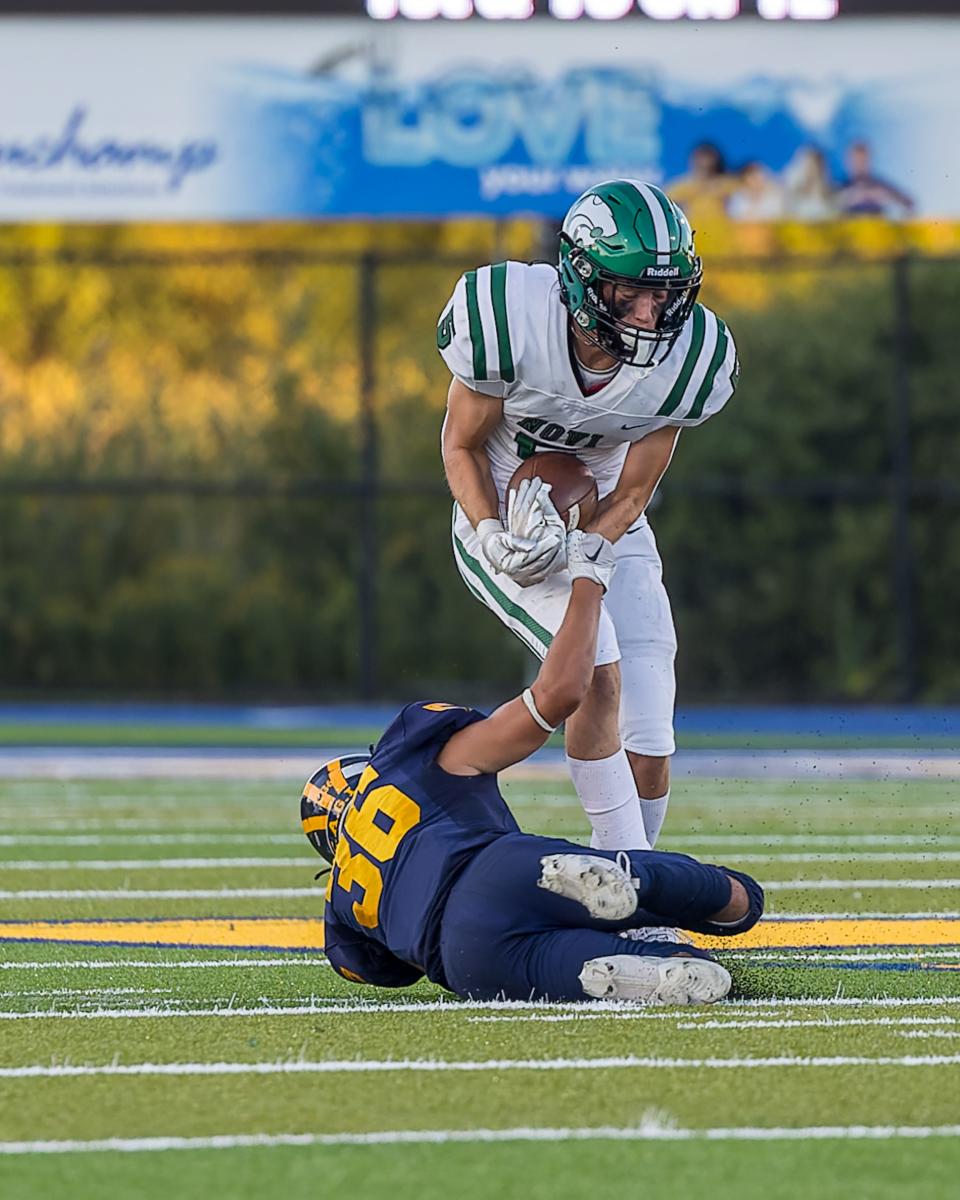 Novi's Jaden Vondrasek, who caught two touchdown passes, runs over Hartland's Bodie Abbey during the Wildcats' 14-7 victory Thursday, Aug. 31, 2023.