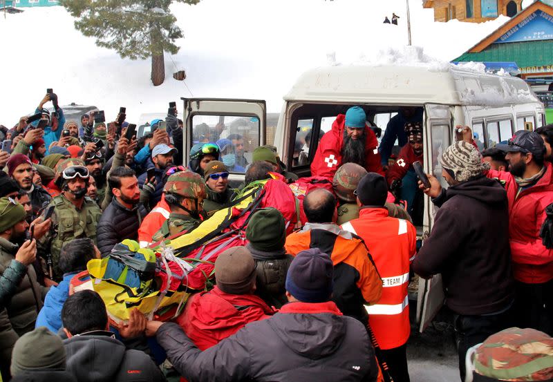 Security force personnel carry the body of a foreign skier, who was killed after an avalanche hit in the Affarwat area, in the ski resort of Gulmarg
