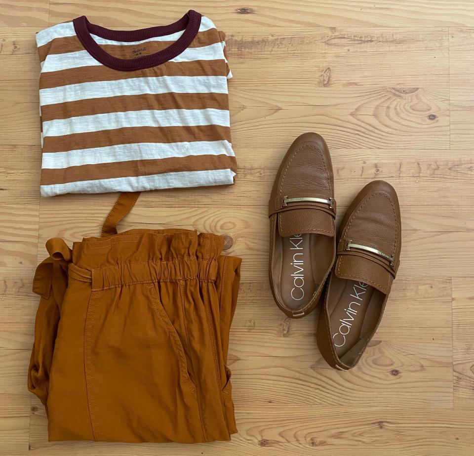 striped T-shirt, paper-bag pants, and loafers on a wood floor