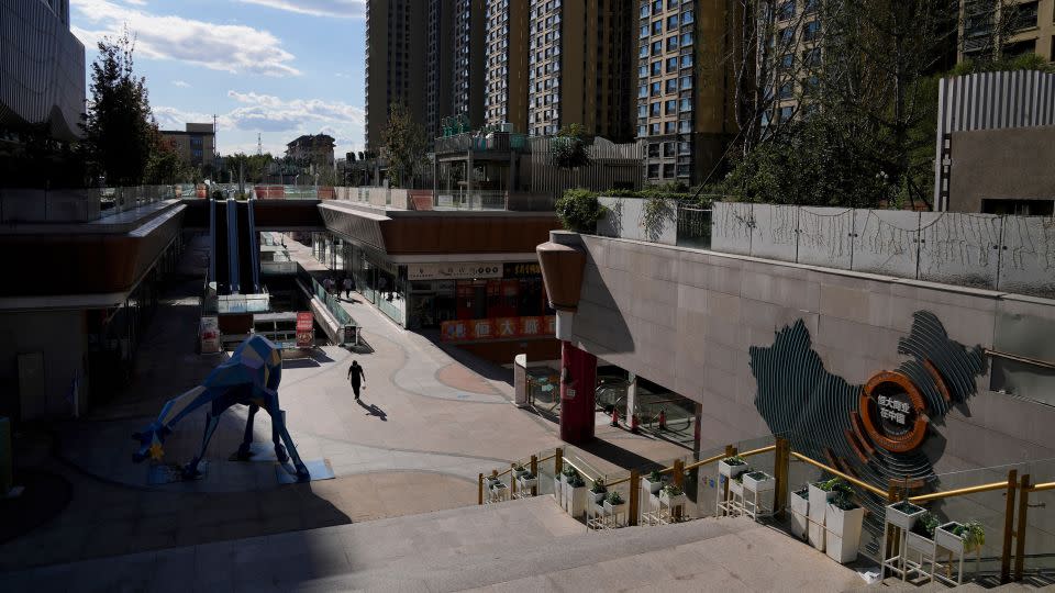 A man walks through a quiet Evergrande city plaza past a map showing Evergrande development projects and its apartment buildings in Beijing, Tuesday, Sept. 21, 2021. - Andy Wong/AP
