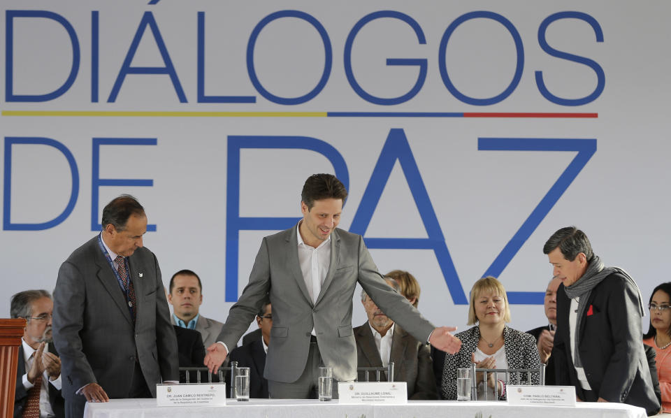 Ecuador's Foreign Minister Guillaume Long, center, welcomes National Liberation Army (ELN) representative Pablo Beltran, right, and Colombia's government representative Juan Camilo Restrepo, left, during a ceremony marking the start of formal peace talks in Quito, Ecuador, Tuesday, Feb. 7, 2017. (AP Photo/Dolores Ochoa)