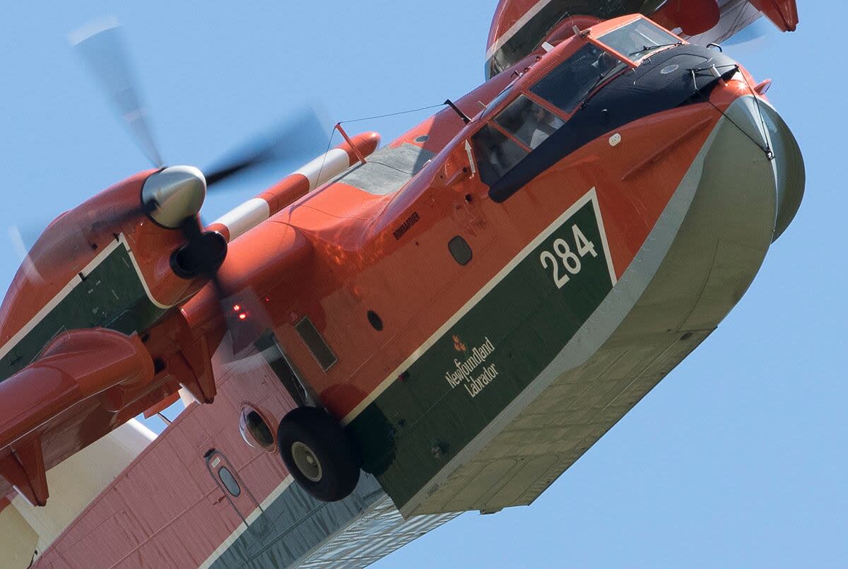 A Newfoundland and Labrador government water bomber flies over a fire in Cappahayden in July 2018. 