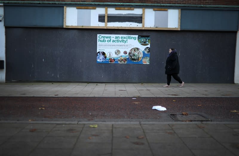 Woman walks past a boarded-up retail unit in the centre of Crewe