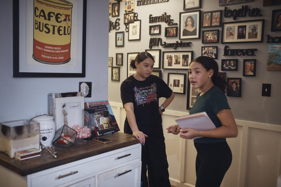 Grace Durham, 11, right, talks with her 17-year-old sister Gabriela, in a hallway of their apartment, Saturday, Jan. 27, 2024, in New York. It is hard to be a teenager today without social media. For those trying to stay off social platforms at a time when most of their peers are immersed, the path can be challenging, isolating and at times liberating. It can also be life-changing.(AP Photo/Andres Kudacki)