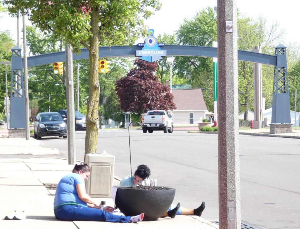 From left, Amber Ritchie and Heather Traxler, who work in Dr. Sarah Metzger’s office on North Seltzer Street in Crestline,  work on painting a flower pot for a competition between local medical offices on Thursday morning. Like the new arch visible in the background, it’s part of efforts to improve the appearance of downtown Crestline.