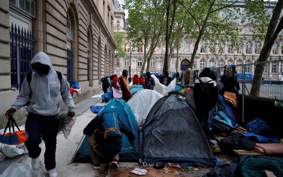 A migrant walks past tents during the evacuation of their camp on Place Saint-Gervais near Paris city hall